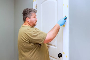 Çağdaş ev ortamında insan kapı çerçevesine dokunurken yenileme çalışmaları devam ediyor.