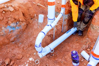 İşçi siperdeki PVC borularını bağlıyor. İnşaat alanında düzgün bir hizalama sağlıyor.