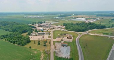 Kırsal kesimde güneşli bir günde ağaçlar ve yollarla çevrili bir inşaat alanı görülebilir..