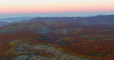Görkemli tepeler, güneş batarken canlı sonbahar renkleri sergiliyor ve huzurlu bir akşam atmosferi yaratıyor..