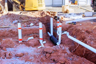 İşçiler yakınlardaki araç kazıcı ekipmanlarıyla yerleşim bölgesine drenaj sistemi kuruyor..