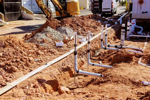 İşçiler, kenar mahallelerdeki inşaat sahasına atık su tesisat pvc boruları kuruyor..