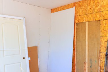 Alçıpan, odanın içine yerleştiriliyor. Kapı ve inşaat malzemeleri sergileniyor.