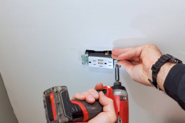 USB portlarının yer aldığı duvar prizi kurulumu, görev için matkap kullanımı.