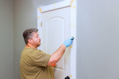 Tamirci ahşap kapı çerçevesini kullanarak dikkatlice dokunuyor. Odaya ahşap dolgu malzemesi koyuyor.