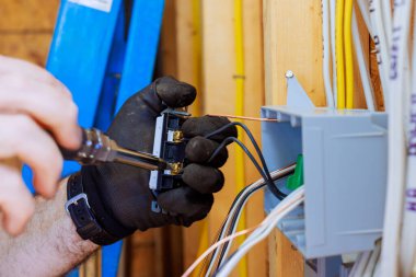 Elektrik tesisatçısı ev tadilatı sırasında kabloları duvara monte ederek elektrik kutusuna bağlıyor