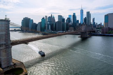 New York 'taki Brooklyn Köprüsü' nün ufuk çizgisini aydınlatan tekne süzülürken, Doğu Nehri üzerinde Manhattan 'da uzun binalar beliriyor..