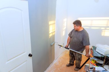 Marangoz inşaat sırasında evde rulo ile boyayı dikkatlice duvara uygular.