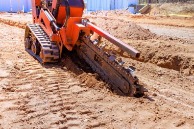 Kazıcı inşaat sahasında faaliyet gösteriyor, inşaat faaliyetlerine hazırlanırken toprakta çukur kazıyor.