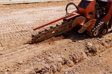 Hendek makinası inşaat alanındaki toprağa hendek kazıyor.