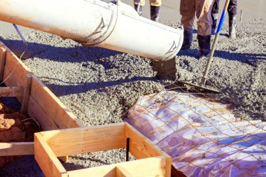 İnşaat işçileri inşaat alanındaki çimentodan ahşap işçiliğe ıslak çimento dökülüyor beton temeller için yapısal takviye sağlayan inşaat inşaat demiri şebekesine çimento dökülüyor..