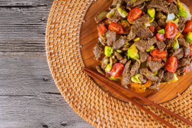 Cızırdayan sığır eti şeritleri Asya mutfağı ile karıştırılmış lezzetli sebzeler ağız sulandırıcı tabakları kırsal ahşap tabakta oluşturur..