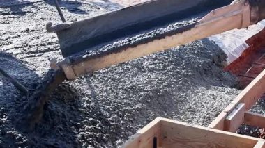İşçiler inşaat alanındaki ahşap formlara taze beton dökerler.