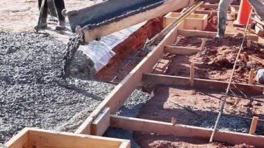 Beton karıştırıcı yeni kaldırım için güçlendirilmiş parmaklıklara taze beton döküyor