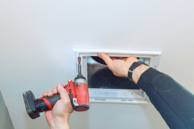 Müteahhit, iş günlerinde ev geliştirme ortamında havalandırma kapağını güvence altına almak için elektrikli araç kullanır