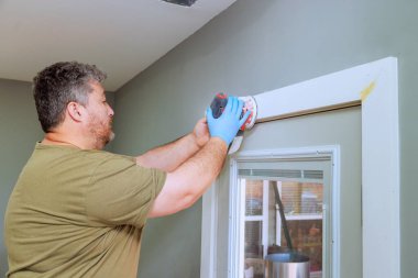 Müteahhit, ev yenileme çalışmaları sırasında kapı çerçevesini dikkatlice zımparalıyor