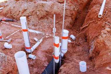 İşçiler, atık su tesisatı için yeni döşenmiş PVC boru siperleriyle inşaat alanı hazırlıyorlar..