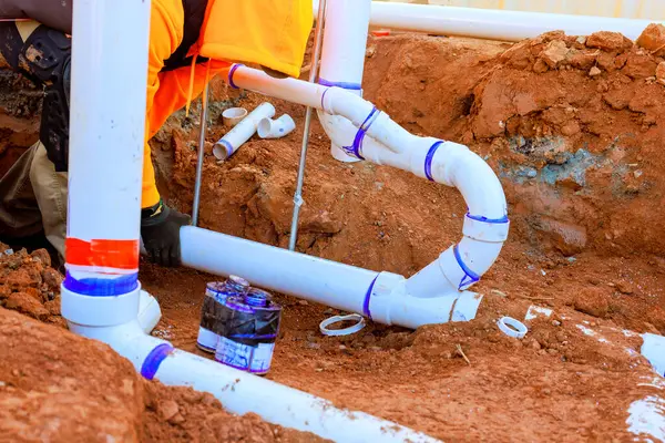 Müteahhit, iş günü boyunca inşaat alanındaki siperlere plastik kanalizasyon boruları döşemekle meşgul.