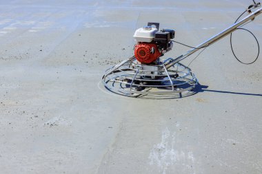 İşçi, açık inşaat alanında yeni dökülmüş betonu düzleştirmek için mala makinesini çalıştırıyor. Kusursuz bir bitiriş sağlıyor..