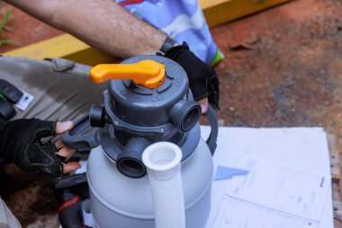 Teknisyen evde yüzme tulumbası filtre sistemini inceliyor, havuz bakımına hazırlanıyor.