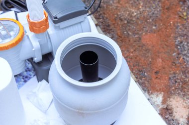 Kurulum süreci yüzme havuzu arka planında filtreleme sistemi bileşeninin bağlanmaya hazır olduğunu gösteriyor.