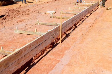 İşçiler iş günü inşaat sahasında temel için ahşap formlar hazırlıyorlar.