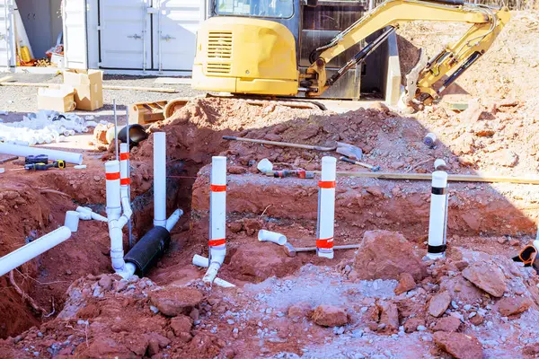 İşçiler yakınlardaki inşaat sahasına atık su tesisat boruları kuruyor..