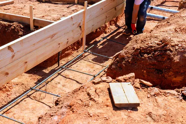 İnşaat işçisi inşaat alanında yeni vakıf için inşaat çubuğu çerçeveleri kuruyor.