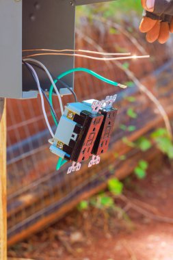 Bir birey, iş gününün altındaki bahçe ayarlarında elektrik kablolarını bağlantı kutusuna bağlar