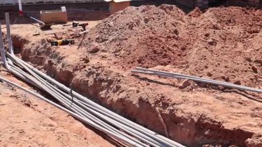 İşçiler, gelecek altyapı atık su boruları tesisatı için kazılmış toprak boruları olan inşaat sahası hazırlıyorlar..