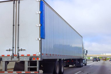 Yük kamyonu, bulutlu koşullar altında birkaç küçük araçla birlikte Amerikan otoyolunda ilerliyor..