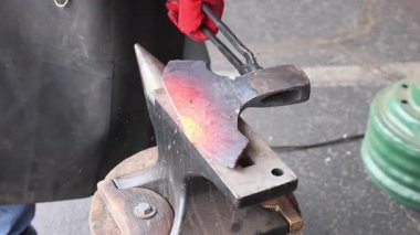 Demirci, balta yapımı sırasında ustaca parlayan metal parçasını çekiçle şekillendirir.