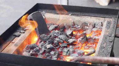 Sıcak kömürler parıldıyor. El sanatları ustası metal balta yapımında çalışıyor. Meşgul demircilikte ustalıkla gösterilen gösterilerde kıvılcımlar yaratıyor..