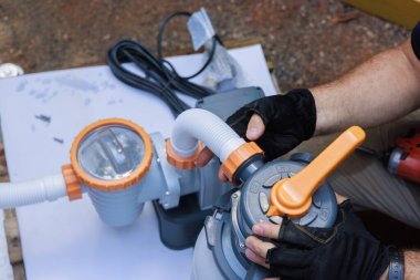 Bireysel, su pompasının parçalarını dışarıdaki havuz filtresine bağlıyor.