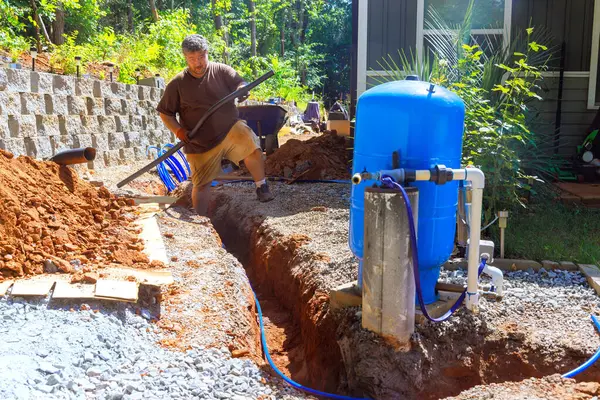 İşçi aktif olarak boru PEX Artesian su kuyusu sistemi kurulumu için siper hazırlıyor