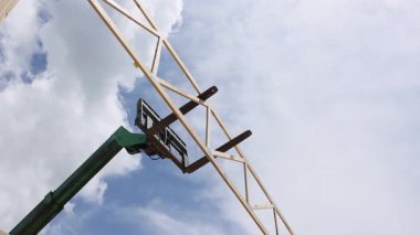 İnşaat işçileri, çerçeve montajı altındaki inşaat sahasında büyük ahşap kirişler açmak için tele-denetleyici vinç kullanıyor.