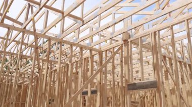 İşçiler parlak mavi gökyüzünün altında kirişlerle ahşap çatı kirişleri inşa ediyorlar..