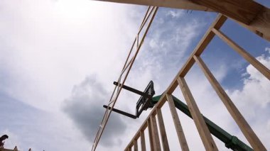 İşçiler, bulutlar yukarıda toplanırken ahşap kirişleri yapım aşamasında yerleştirmek için tele idareciyi kullanıyor..