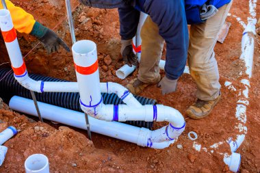 İnşaat işçileri sipere kanalizasyon boruları dökerek su akışı için uygun tesisatı sağlıyorlar..