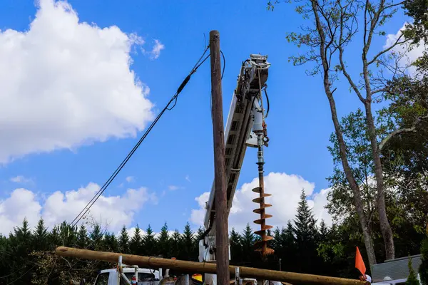 İnşaat ekibi, tamirat sırasında banliyödeki elektrik hattını delmek için güçlü bir matkap kullanıyor.