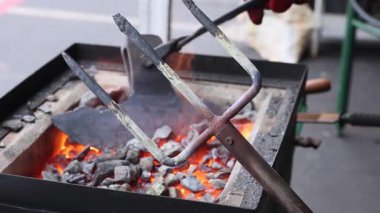 Demirci bahçe çatalı yaparken, sıcak metali örs olarak kullanır, oturumu geleneksel hale getirirken çekiç kullanır.