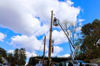 Elektrik işçileri elektrik hatlarını onarmak için asansör kamyonları kullanırken, iş günlerinde konut alanlarında güvenliği sağlıyorlar..