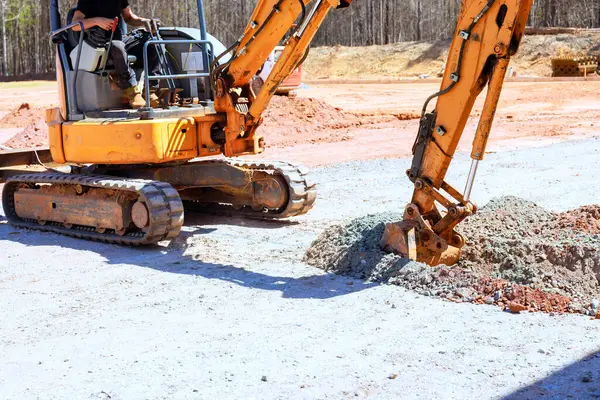 İnşaat alanında ağır makineler çalışıyor, iş günlerinde çakıl kazıyorlar.