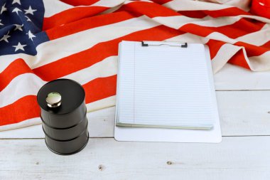 Beyaz ahşap yüzey üzerine yayılmış bir Amerikan bayrağı üzerinde yağ varilleri silindirik konteynır panosu.