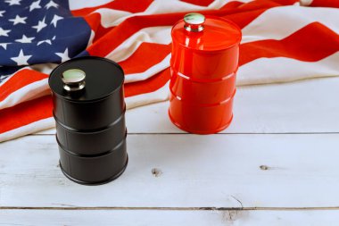 Petrol varilleri, bir siyah, bir kırmızı, Amerikan bayrağının yanında ahşap bir yüzeye yerleştirilmiştir..