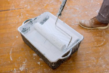 İşçi, evi restore ederken boya silindirini beyaz boyayla doldurdu..