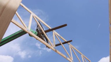 Telekonsor vinç, çerçeve oluşturma işlemi sırasında inşaat alanında ahşap kirişleri kaldırıyor.