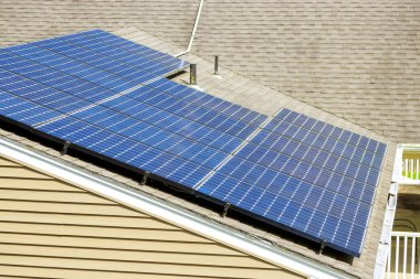 Güneş panelleri enerji tasarrufu altındaki sakin banliyö bölgesindeki evin çatısında enerji yakalıyor.