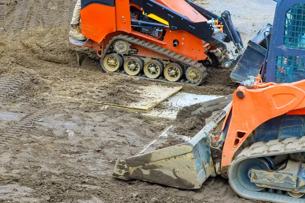 İnşaat inşaatını hazırlamak için ıslak zeminde ağır makineler çalışıyor.