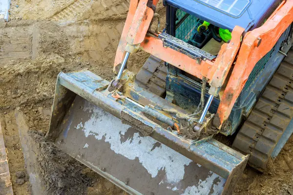 Traktör ekipmanları inşaat alanında çalışır, gündüz saatlerinde toprak yığınlarını taşır.